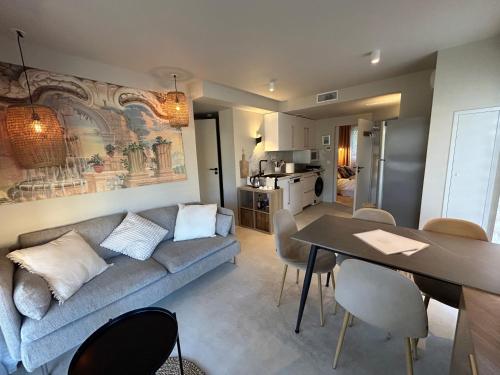 a living room with a couch and a table with chairs at Bas de villa la sablhyeres- 300m Plage de la Capte - 2 hébergements disponibles in Hyères