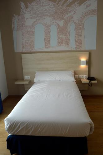 a large white bed in a bedroom with a wall at Hotel Balneario de Graena in Graena