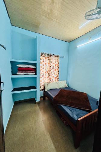 バガモンにあるPheonix home stayの青い壁の小さな客室で、ベッド1台が備わります。