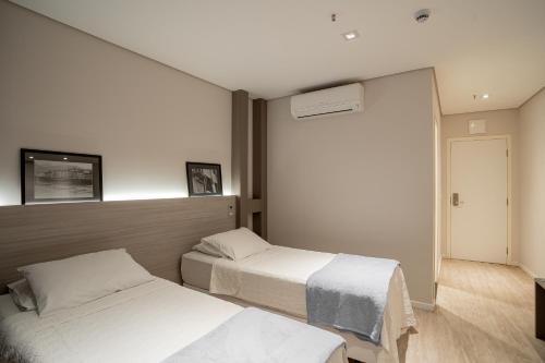 a bedroom with two beds and a window at Zahara Hotel in Limeira