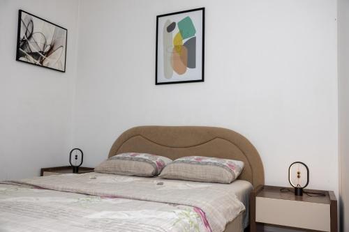a bedroom with a bed with two tables and two pictures at AVA Apartment Istočno Sarajevo in Lukavica