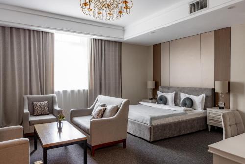 a hotel room with a bed and chairs and a chandelier at Mountain View Residence Hotel in Almaty