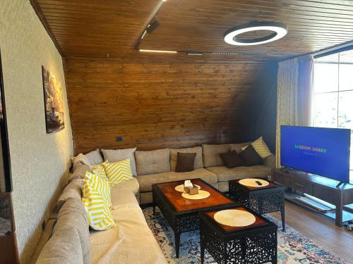 a living room with a couch and a flat screen tv at Umm Aljulud Cottages 02 in Ajloun