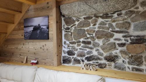 a living room with a stone wall and a couch at L'Orri in Dorres
