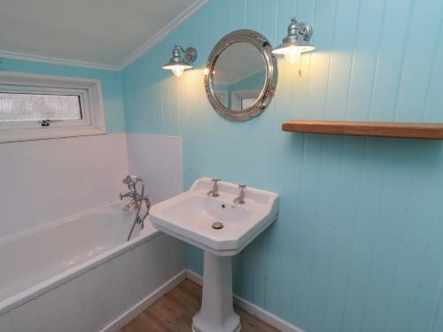 a bathroom with a sink and a tub and a mirror at Braeburn in Bamburgh