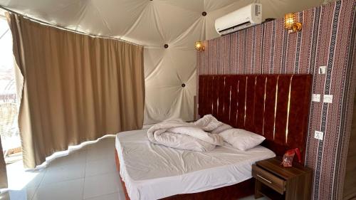 a small bedroom with a bed with a canopy at Wadirum Leen camp in Wadi Rum