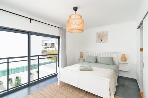 a bedroom with a white bed and a balcony at Spacious house in Olhao in Quelfes