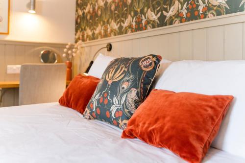 a bed with orange and black pillows on it at The Harbour Guest House in Irvine