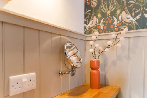 an orange vase sitting on a wooden table with a mirror at The Harbour Guest House in Irvine