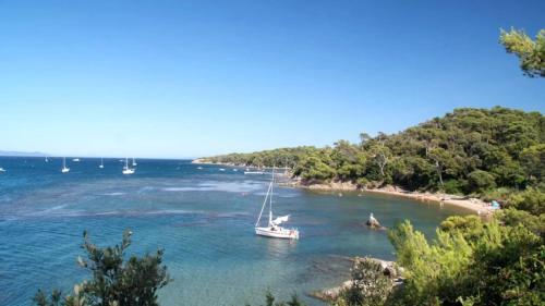 a boat in the water next to a beach at ZEcamping 3 à 150m de la plage cadre unique de la presquîle de Giens in Hyères