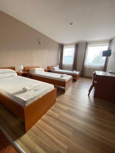um quarto com três camas e duas janelas em Hotel Ferihegy em Vecsés