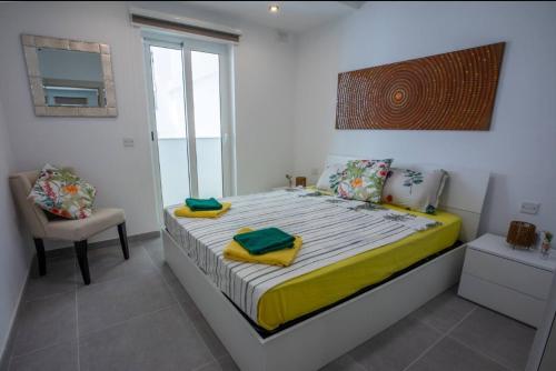 1 dormitorio con 1 cama con silla y ventana en Elegant 2BR Seaside Stay, Balluta Bay Oasis P2, en Sliema