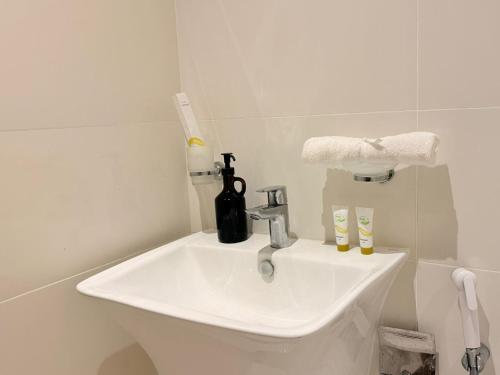 un lavandino bianco in bagno con una bottiglia sopra di Central Muscat 1BR Petit Villa a Mascate
