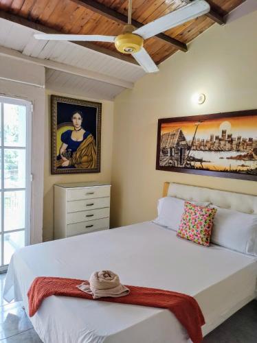 a bedroom with a white bed with a hat on it at Casa Del Pintor in Santa Marta