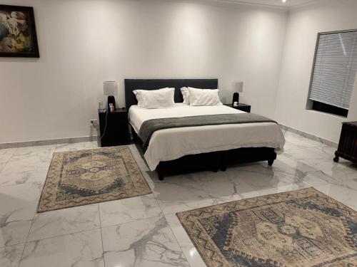 1 dormitorio con 1 cama grande y 2 alfombras en 49 The Hill, en Plettenberg Bay