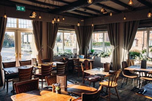 a restaurant with wooden tables and chairs and windows at The Station Restaurant & Bar in Doncaster