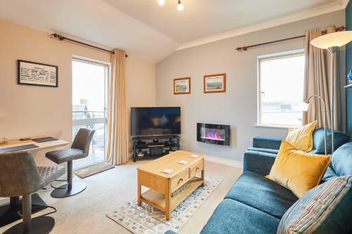a living room with a blue couch and a tv at Host & Stay - The Shipshape in Seahouses