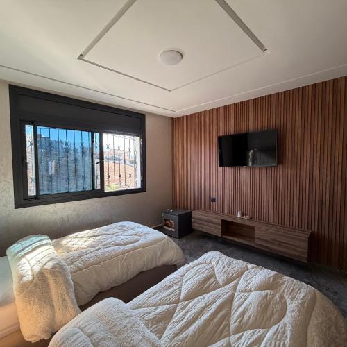 Un dormitorio con dos camas y un televisor de pantalla plana. en Moul Partma Berkane N5, en Berkane