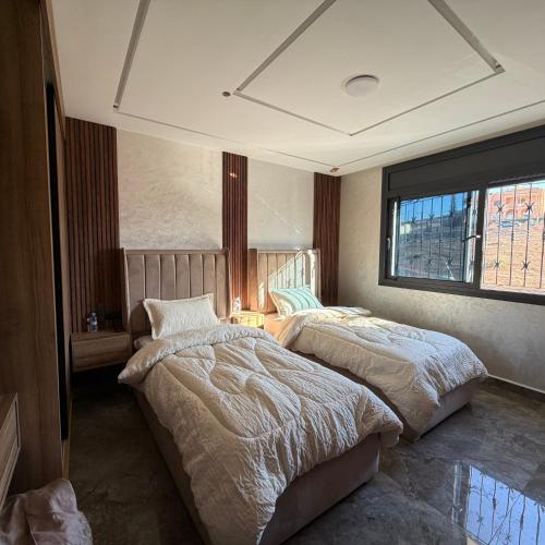 Un dormitorio con dos camas y una ventana. en Moul Partma Berkane N5, en Berkane