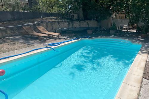 a blue swimming pool with two chairs in it at Gîte du Jonquas in Velleron
