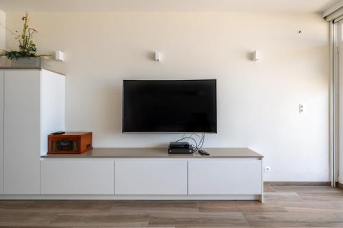 a flat screen tv on a white wall at BEL AIR HOLIDAY - Luxury 2-bedroom apartment with sea view & jacuzzi T48 in Ostend