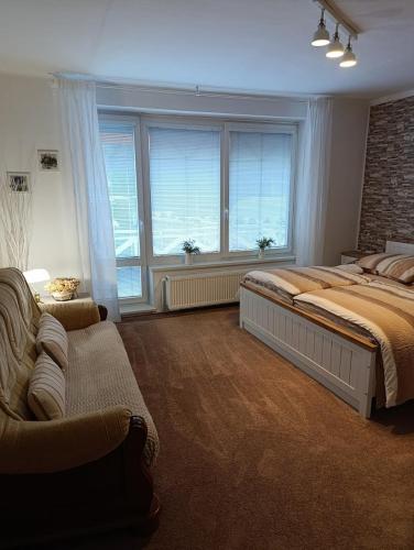 a bedroom with a bed and a couch and windows at Apartment Krnov in Krnov