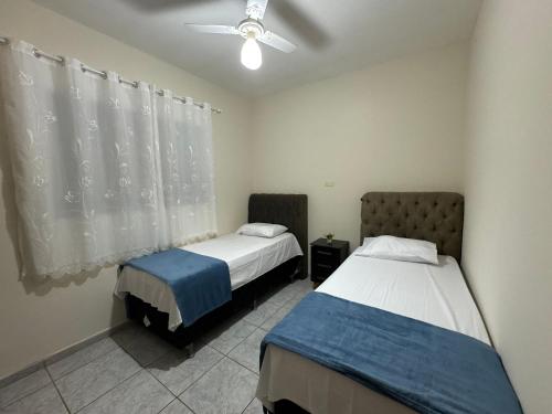 a bedroom with two beds and a ceiling fan at Casa completa, ar e vaga, perto parque Ecológico in Ourinhos