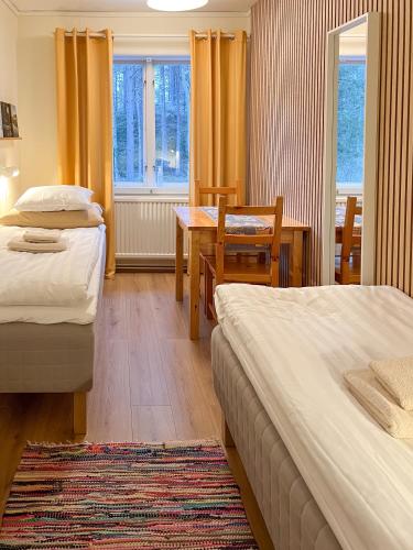 a hotel room with two beds and a table and chairs at Fulufjällsgården in Mörkret