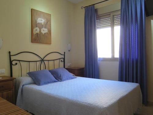 馬薩龍港的住宿－Pensión La Venta，一间卧室配有一张带蓝色窗帘的床和一扇窗户