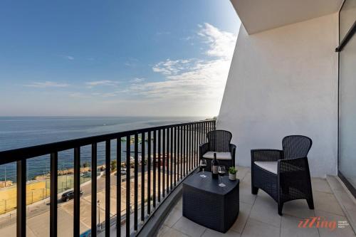 a balcony with chairs and a view of the ocean at A Stylish Seaside Holiday Home in St Paul's Bay in St. Paul's Bay