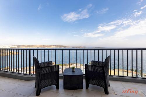 a balcony with chairs and a table and the ocean at A Stylish Seaside Holiday Home in St Paul's Bay in St. Paul's Bay