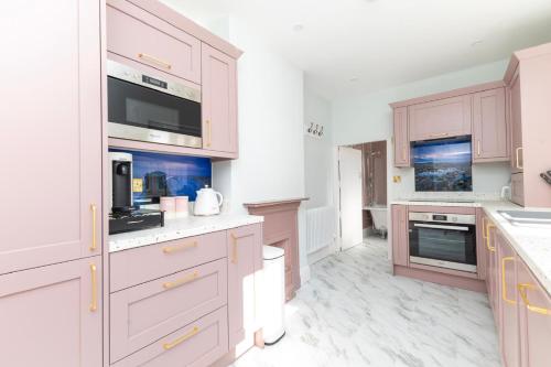 eine Küche mit weißen Schränken und einer Mikrowelle in der Unterkunft Luxury 2 Bedroom Georgian home, garden, Beach access, 6 guests in Bognor Regis