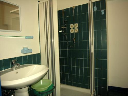 a green tiled bathroom with a sink and a shower at Cannella studio flat Canneto Lipari in Canneto - Lipari