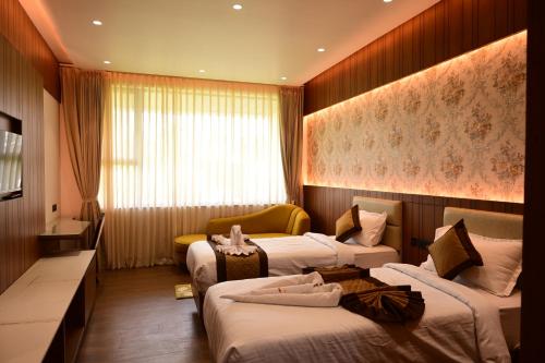 a hotel room with three beds and a couch at IJ Crowne in Mysore