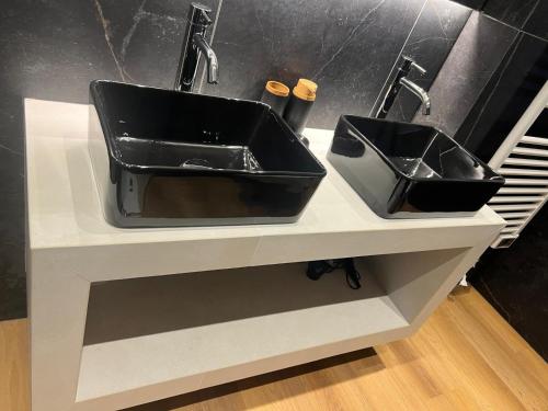 a black bathroom sink with two sinks on a counter at Black Swan Apartment in Peschiera del Garda