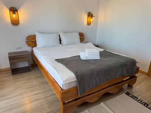 a bedroom with a wooden bed with two towels on it at Pensiunea Roua Brazilor Mărișel in Mărişel