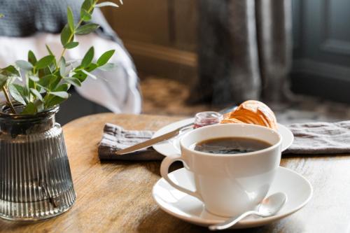 a cup of coffee and a croissant on a table at Irvine Guest House in Irvine