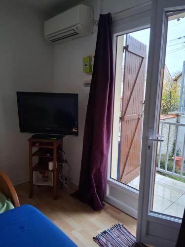 a living room with a television and a sliding glass door at appartement une chambre Champigny-sur-Marne in Nogent-sur-Marne