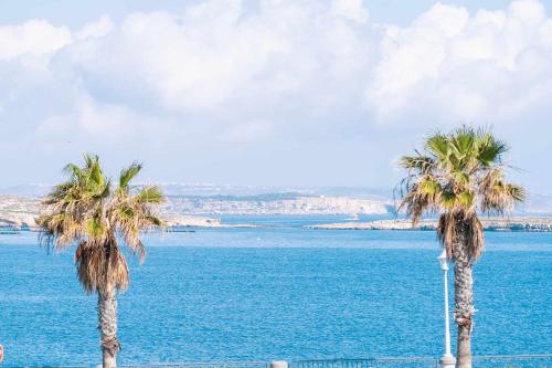 due palme di fronte a un grande specchio d'acqua di Stunning Holiday Villa with a Heated Jacuzzi a San Pawl il-Baħar