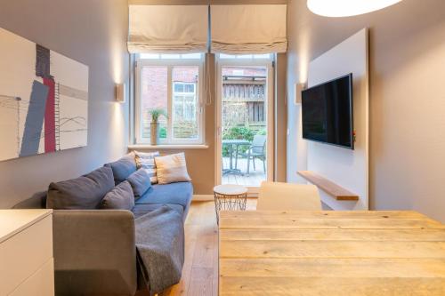 een woonkamer met een blauwe bank en een tafel bij Logierhaus K15 Appartement 1 in Borkum