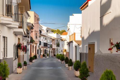 an empty street with white buildings and potted plants at Orange Suite By Alhaurín Loft City in Alhaurín de la Torre