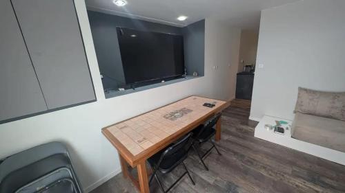 查内勒斯梅肯Appartement charmant à Charnay-lès-Mâcon avec jardin的小房间设有桌子和平面电视