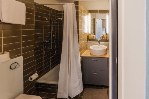 un bagno con vasca, lavandino e doccia di Surfers Oase near Interlaken at lake with pool a Därligen