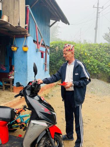 a man is standing next to a motor scooter at Thir bahadur karki's Home 