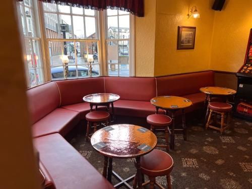 a waiting room with a red couch and tables at The Brunswick Hotel in Bridlington