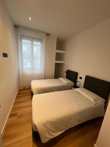 three beds in a room with a window at White Swan Apartment in Peschiera del Garda