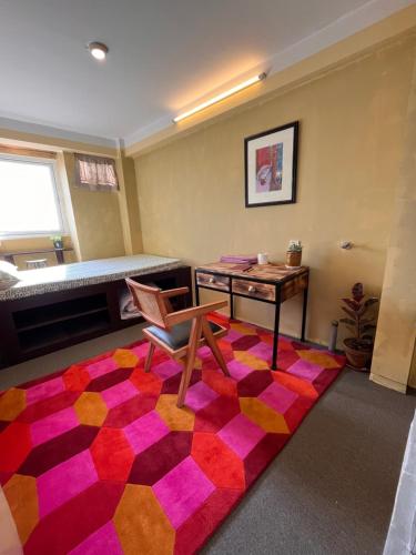 Rooftop apartment front Boudha View في كاتماندو: غرفة بها مكتب وكرسي وسجادة