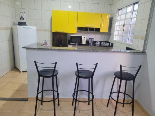 una cucina con tre sgabelli da bar di fronte a un bancone di Casa á 5 minutos do Paraquedismo a Boituva