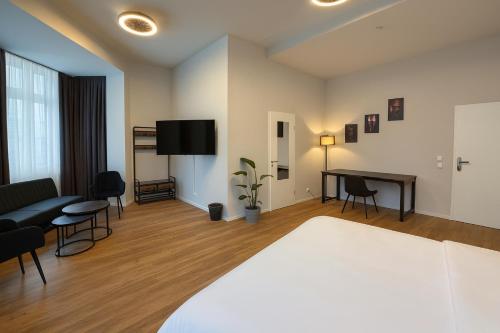 ein Zimmer mit einem Bett, einem Tisch und einem Fernseher in der Unterkunft la Plaza24 in Düsseldorf