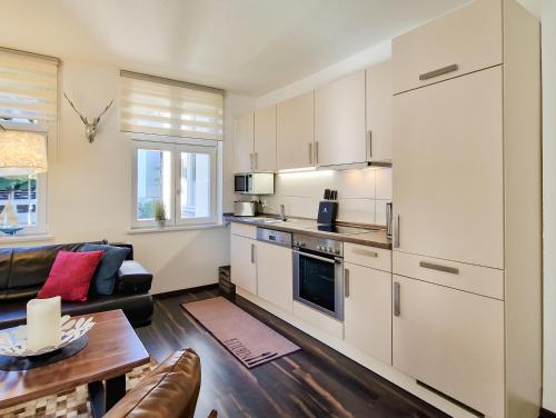 a kitchen with white cabinets and a living room at Brise Villa Emmi App 03 in Heringsdorf